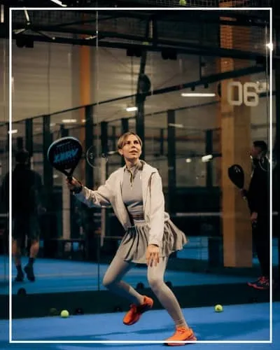 Padel-Spieler auf einem von Glaswänden umgebenen Court