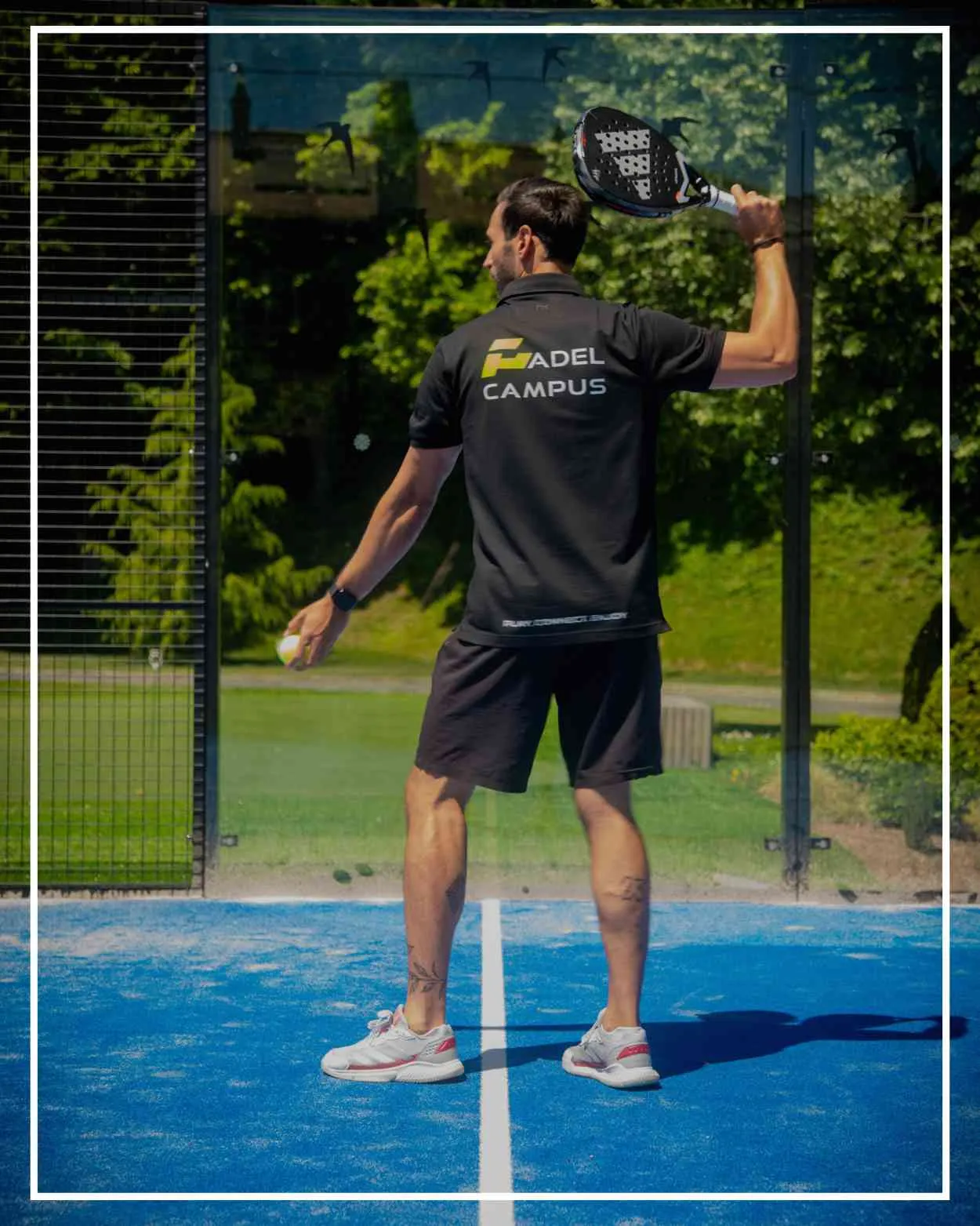 Padel-Spieler auf einem von Glaswänden umgebenen Court